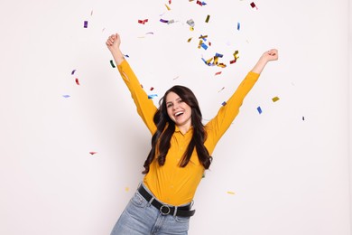 Photo of Happy woman under falling confetti on white background. Surprise party