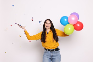 Photo of Happy woman with colorful balloons and flying confetti on white background. Surprise party