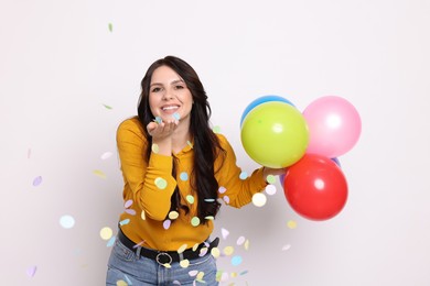 Photo of Happy woman with colorful balloons and confetti on white background. Surprise party