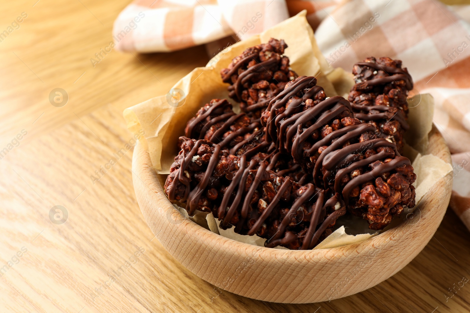 Photo of Delicious chocolate puffed rice bars on wooden table, closeup. Space for text