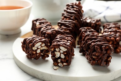 Delicious chocolate puffed rice bars on white marble table, closeup