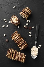 Photo of Delicious chocolate puffed rice bars and spoon on dark gray textured table, flat lay