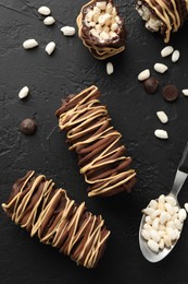 Photo of Delicious chocolate puffed rice bars and spoon on dark gray textured table, flat lay