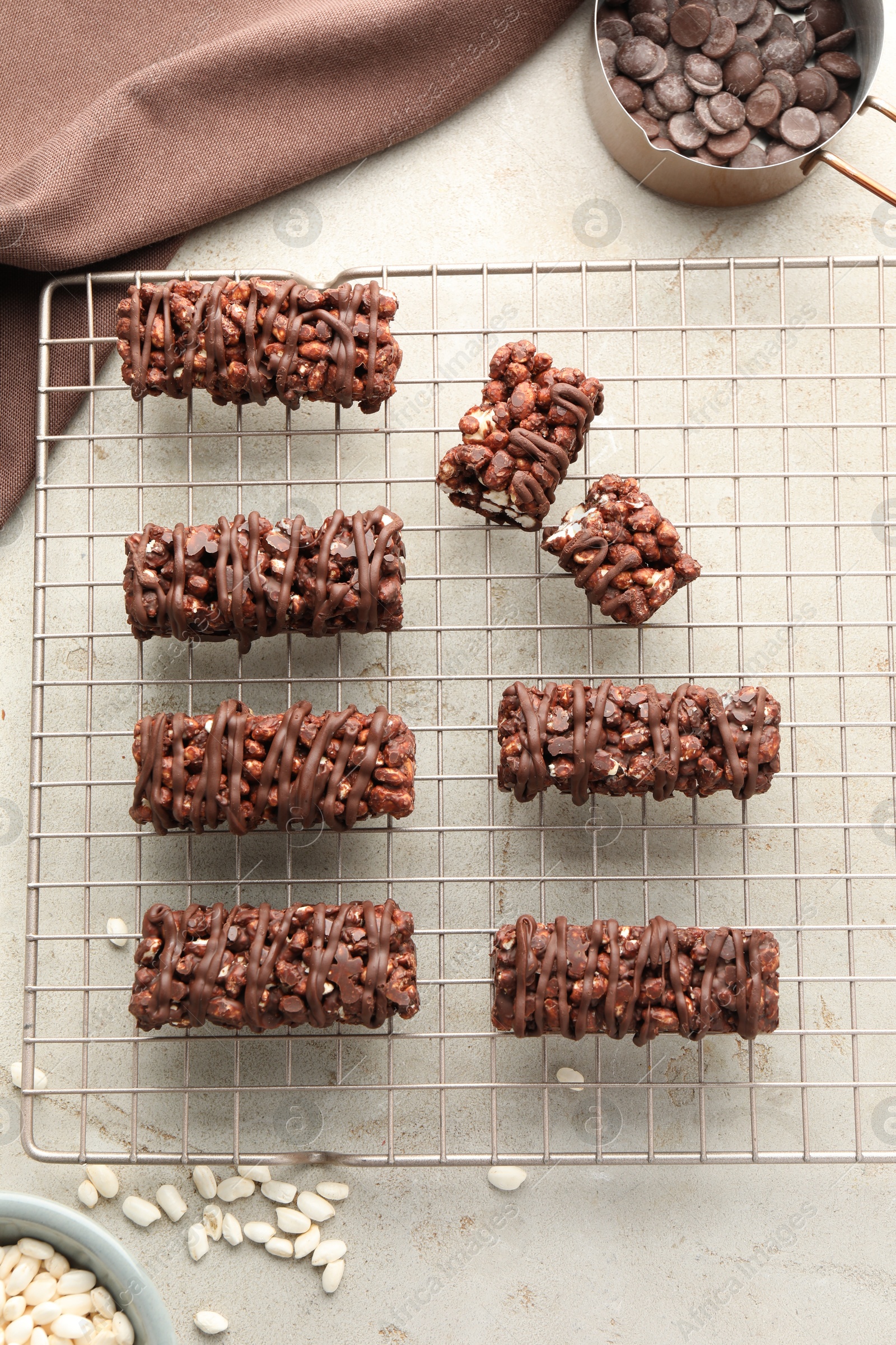 Photo of Delicious chocolate puffed rice bars and candies on gray textured table, flat lay