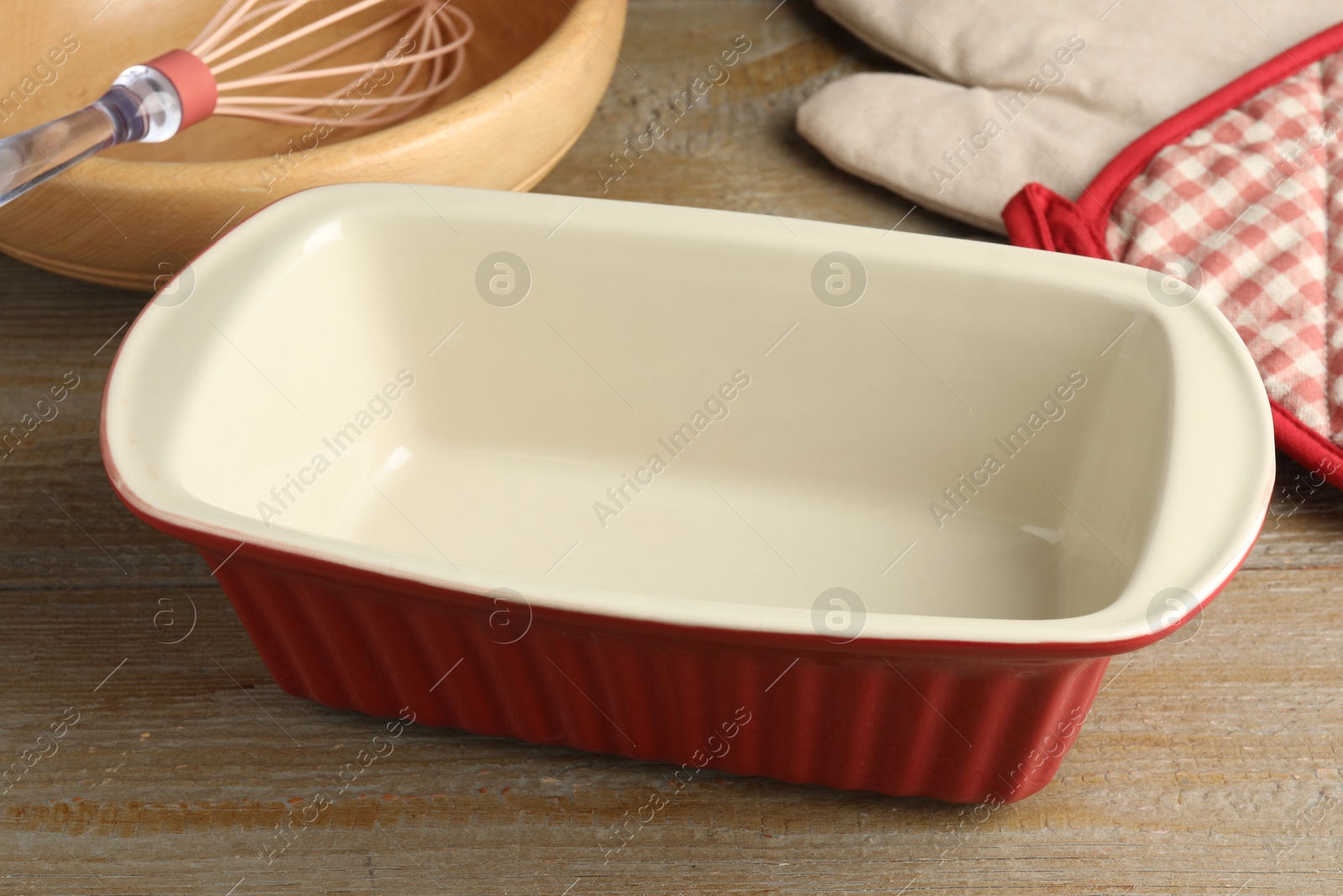 Photo of Ceramic casseroles and other cooking utensils on wooden table, closeup