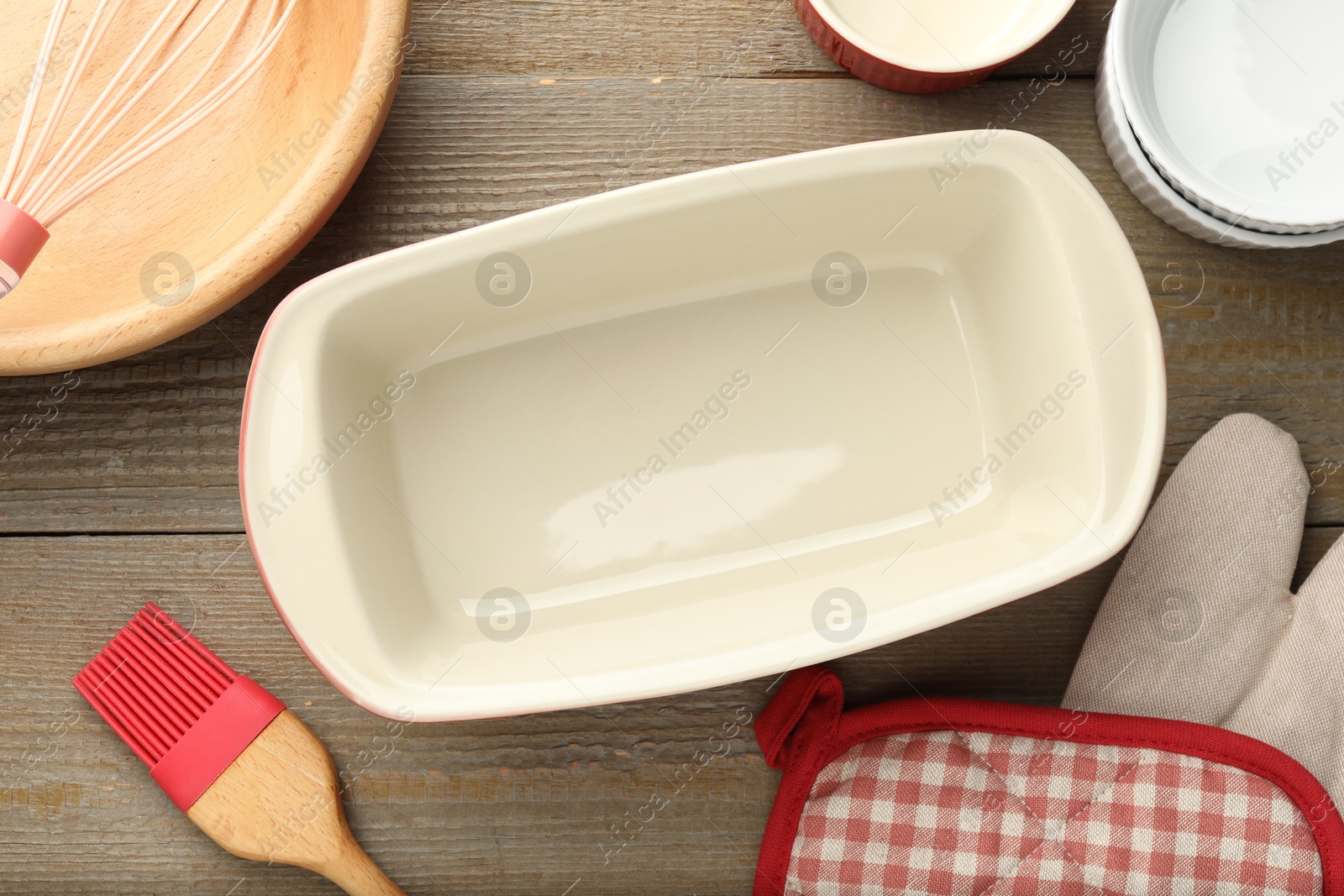 Photo of Ceramic casseroles and other cooking utensils on wooden table, flat lay