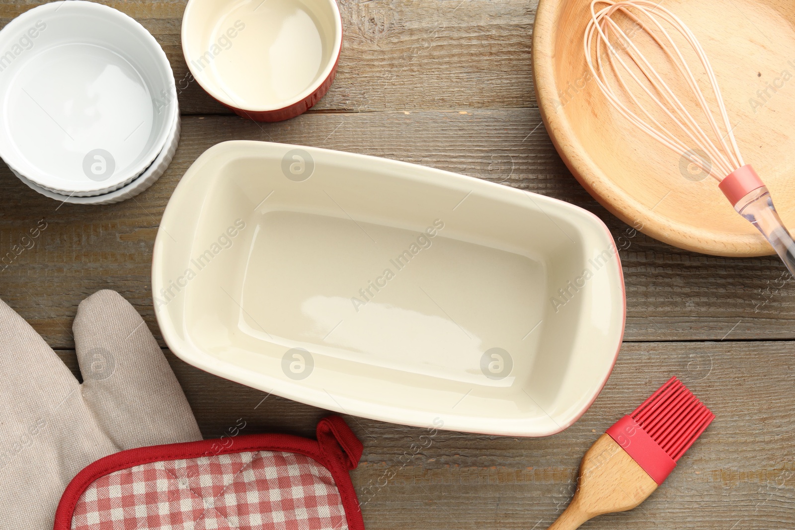 Photo of Ceramic casseroles and other cooking utensils on wooden table, flat lay