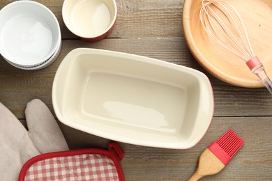 Photo of Ceramic casseroles and other cooking utensils on wooden table, flat lay