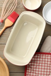 Photo of Ceramic casseroles and other cooking utensils on wooden table, flat lay