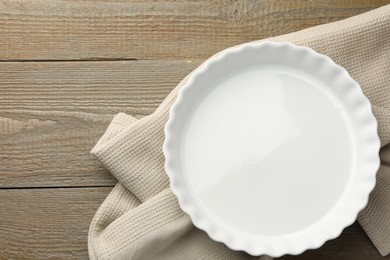 Photo of One ceramic casserole on wooden table, top view. Space for text