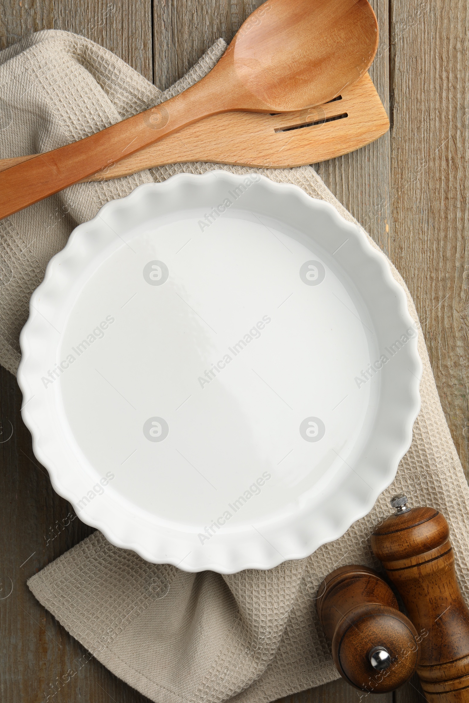 Photo of Ceramic casserole and other cooking utensils on wooden table, flat lay