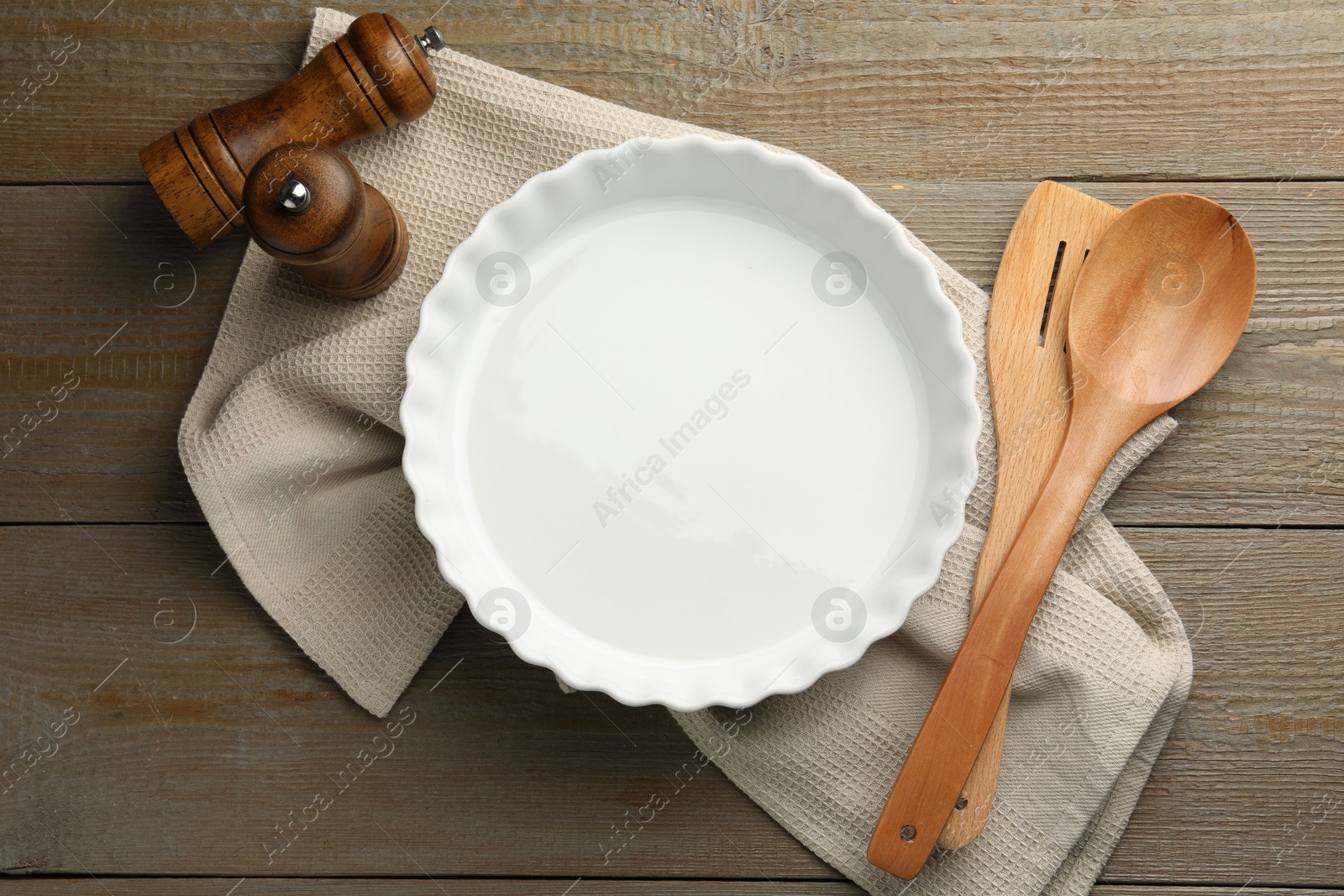 Photo of Ceramic casserole and other cooking utensils on wooden table, flat lay