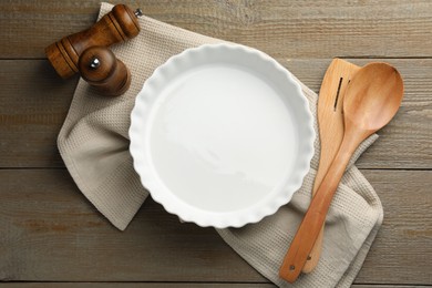 Photo of Ceramic casserole and other cooking utensils on wooden table, flat lay