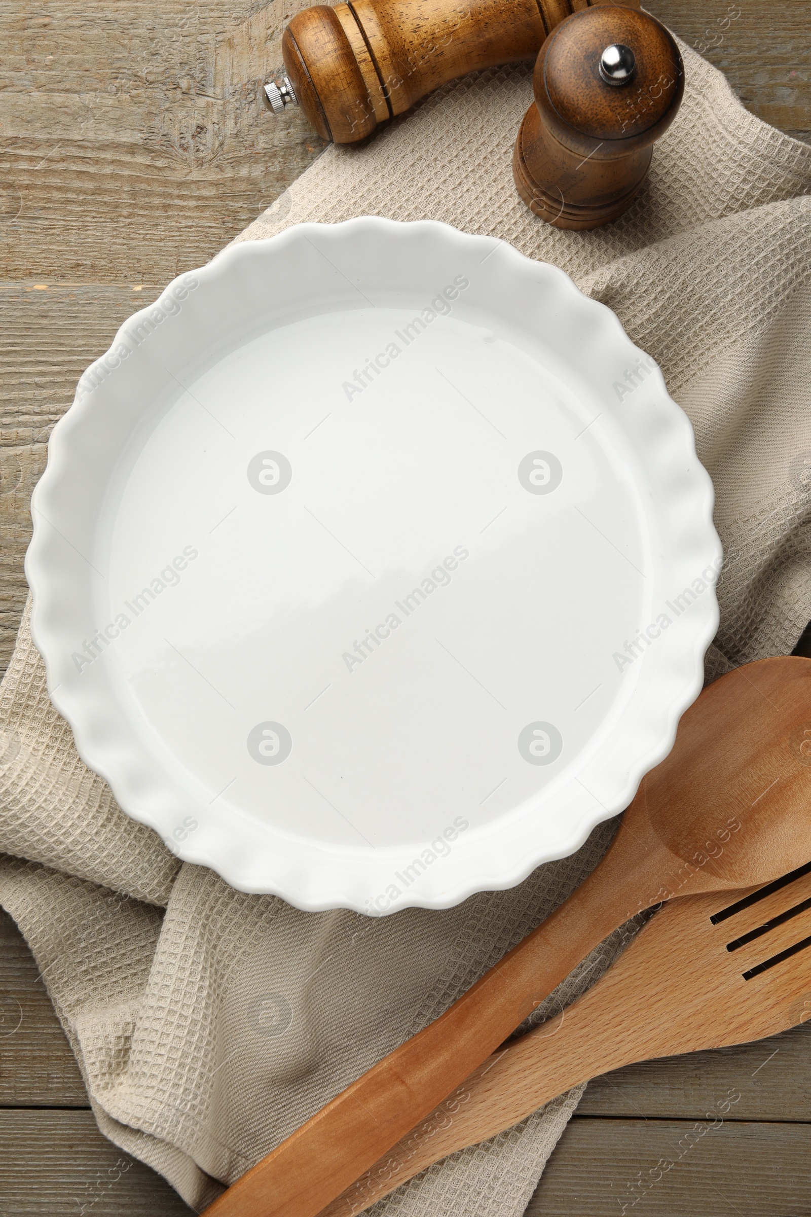 Photo of Ceramic casserole and other cooking utensils on wooden table, flat lay