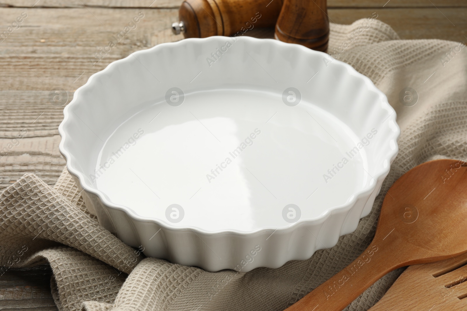 Photo of Ceramic casserole and other cooking utensils on wooden table, closeup