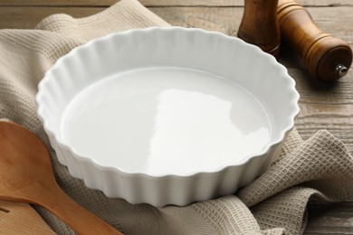 Photo of Ceramic casserole and other cooking utensils on wooden table, closeup