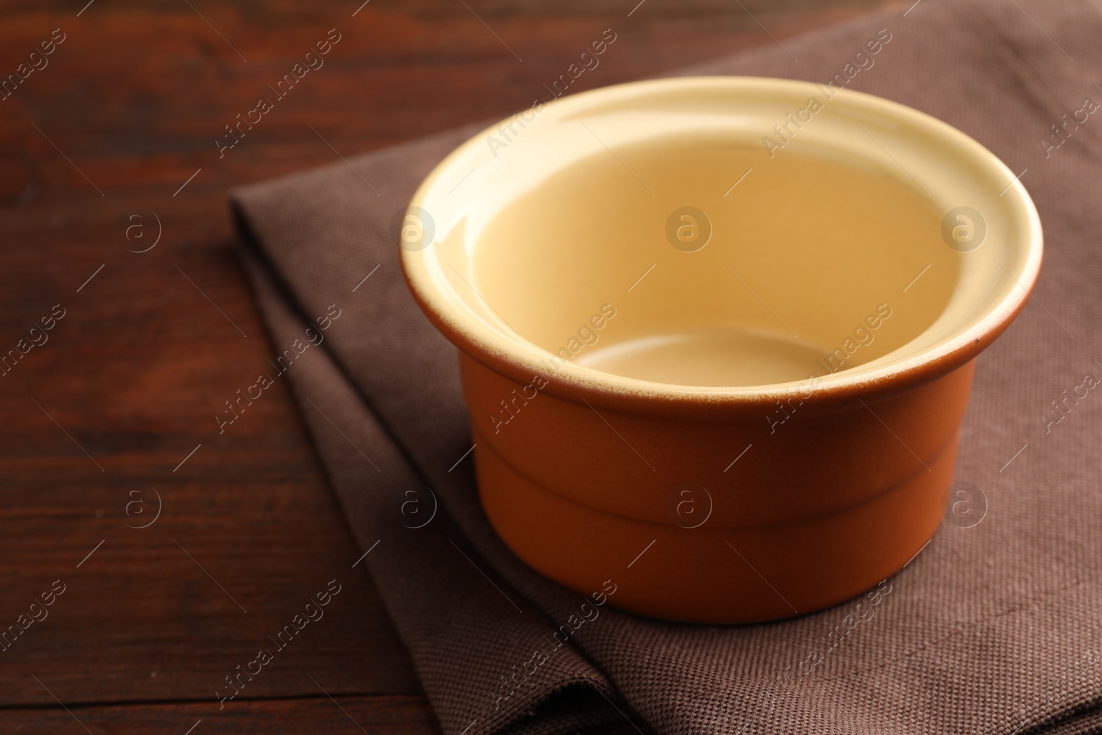 Photo of Ceramic casserole on wooden table, closeup. Space for text