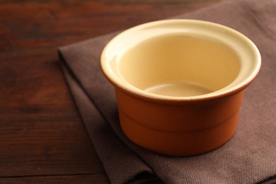 Photo of Ceramic casserole on wooden table, closeup. Space for text