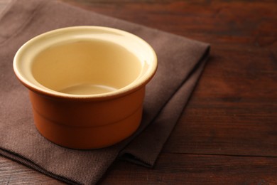 Photo of Ceramic casserole on wooden table, closeup. Space for text