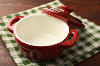 Photo of Ceramic casserole and lid on wooden table, closeup