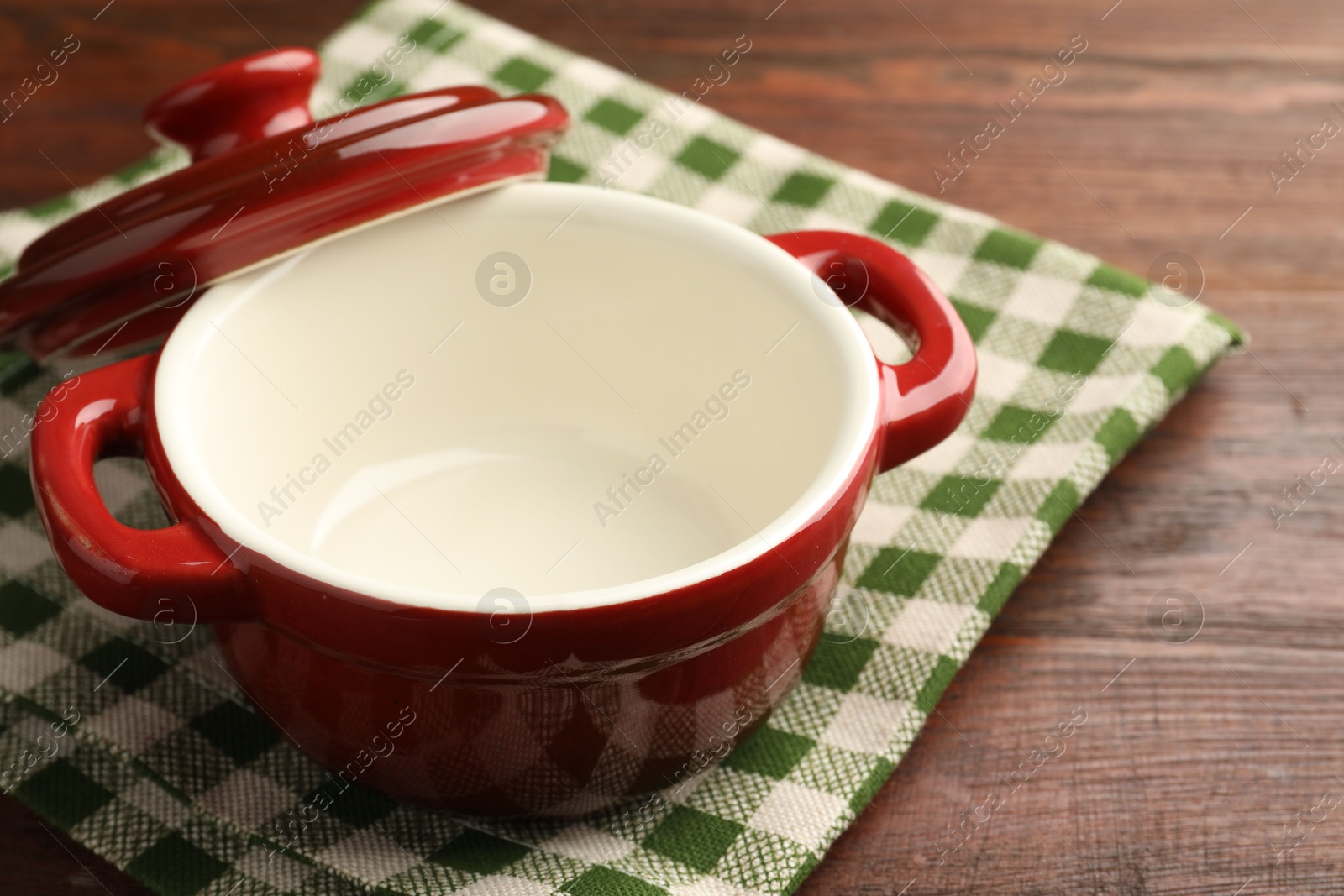 Photo of Ceramic casserole and lid on wooden table, closeup, space for text