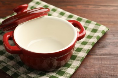 Photo of Ceramic casserole and lid on wooden table, closeup, space for text