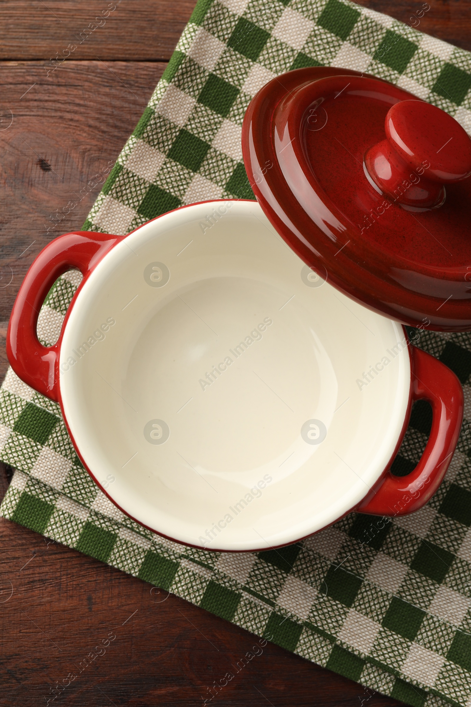 Photo of Ceramic casserole and lid on wooden table, top view