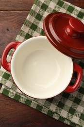 Photo of Ceramic casserole and lid on wooden table, top view