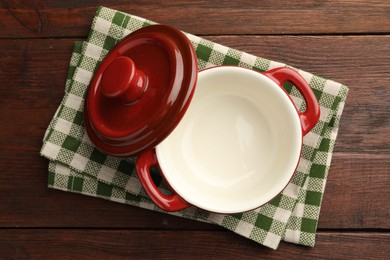 Photo of Ceramic casserole and lid on wooden table, top view