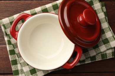 Photo of Ceramic casserole and lid on wooden table, top view