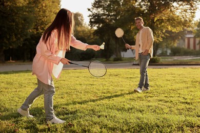 Young woman and man playing badminton in park on sunny day, selective focus