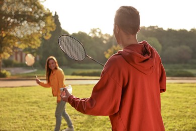 Photo of Young man and woman playing badminton in park on sunny day, selective focus