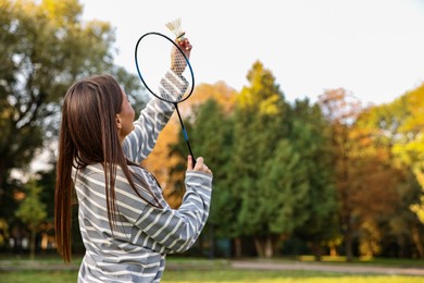 Photo of Young woman with badminton racket and shuttlecock in park, low angle view. Space for text