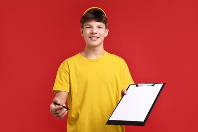 Photo of Teenage boy with clipboard and pen working as courier on red background