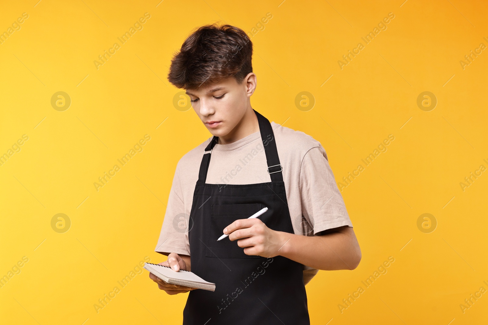 Photo of Boy with notepad taking order in cafe. Work for teenagers