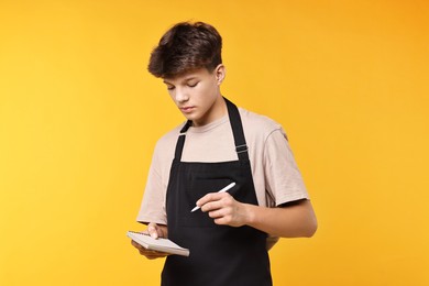 Photo of Boy with notepad taking order in cafe. Work for teenagers