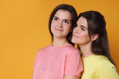 Photo of Portrait of happy twin sisters on orange background, space for text