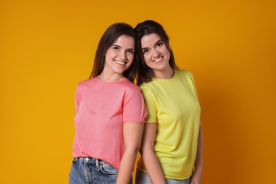 Photo of Portrait of happy twin sisters on orange background