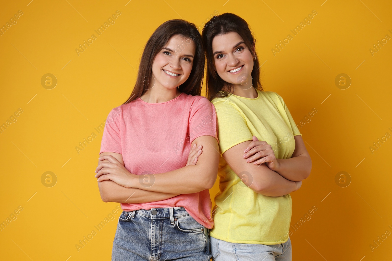 Photo of Portrait of happy twin sisters on orange background