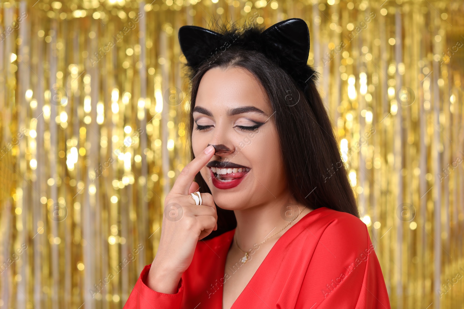 Photo of Beautiful woman with cat makeup and ears on golden background