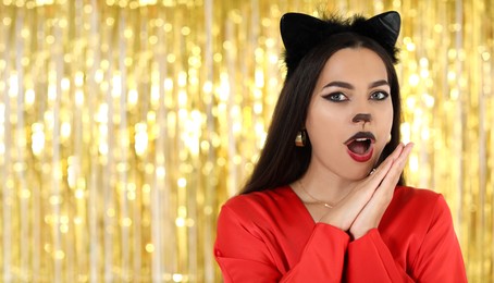 Photo of Emotional woman with cat makeup and ears on golden background. Space for text