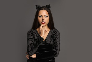 Photo of Attractive woman with cat makeup and ears on grey background