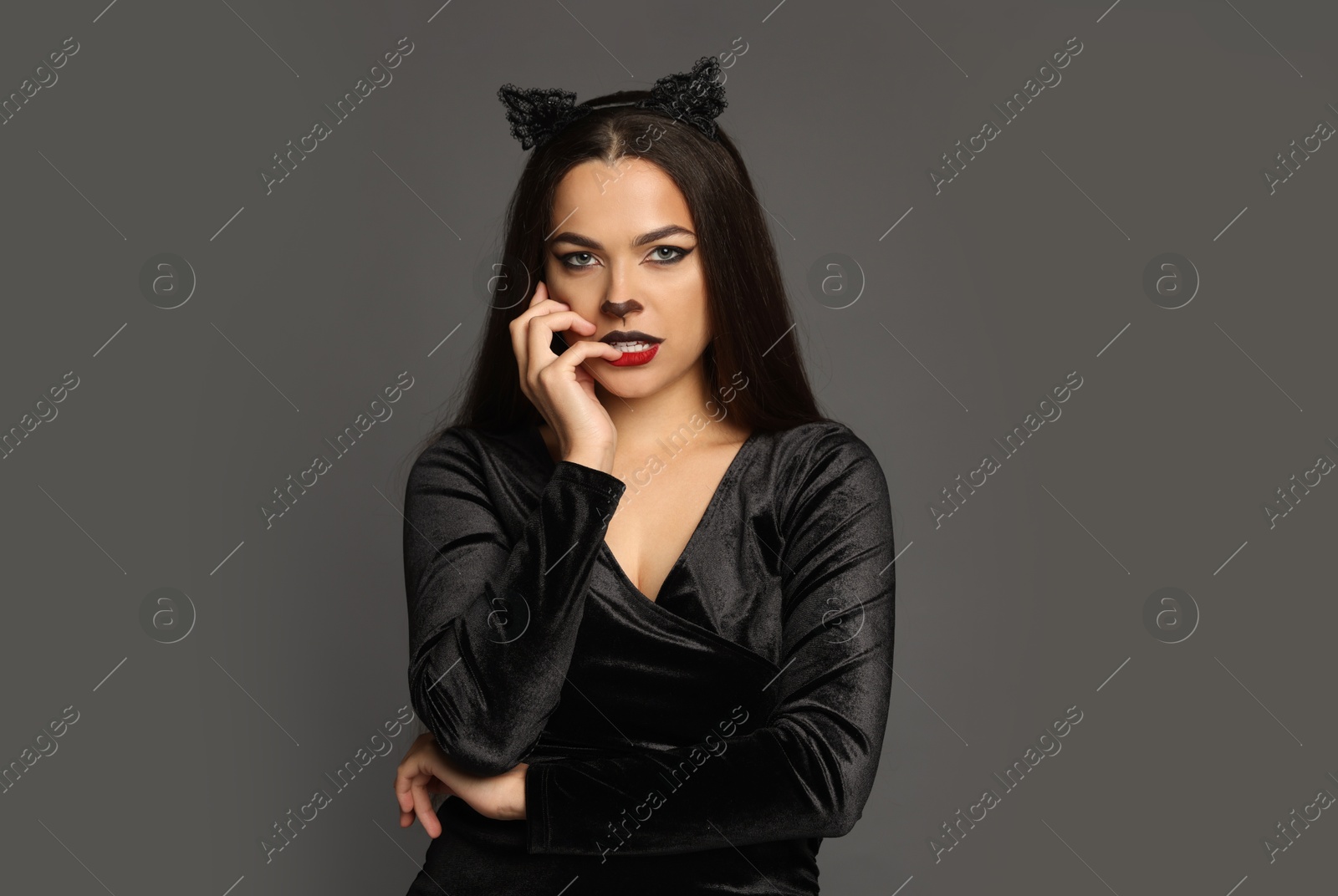 Photo of Attractive woman with cat makeup and ears on grey background