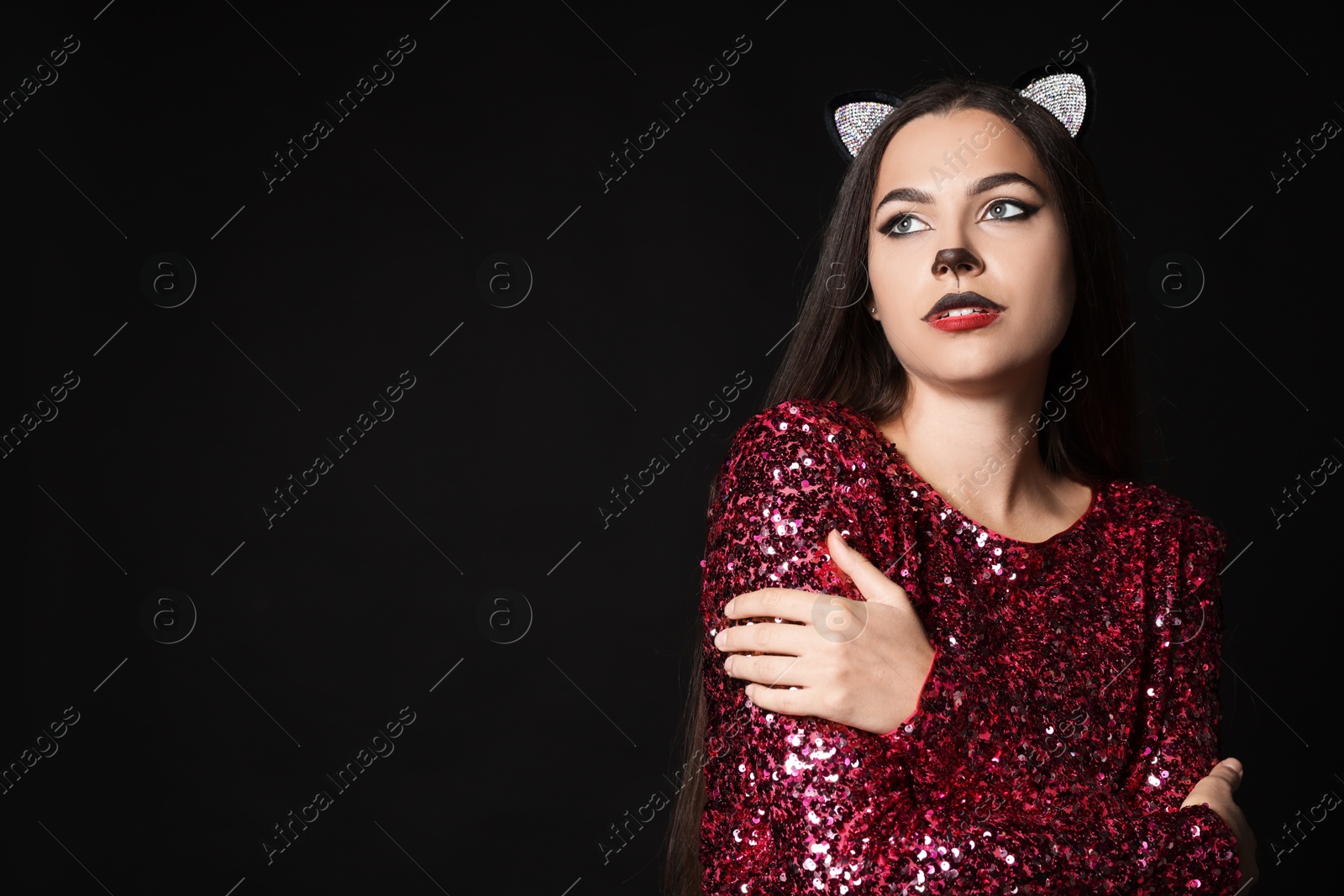 Photo of Charming woman with cat makeup and ears on black background. Space for text