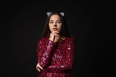 Charming woman with cat makeup and ears on black background