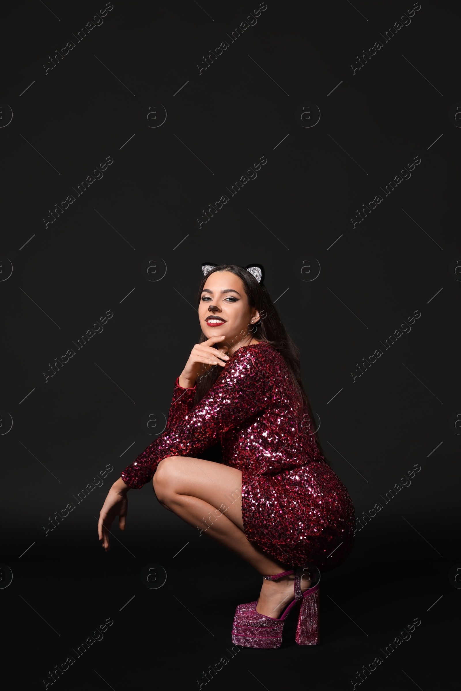 Photo of Charming woman with cat makeup and ears on black background