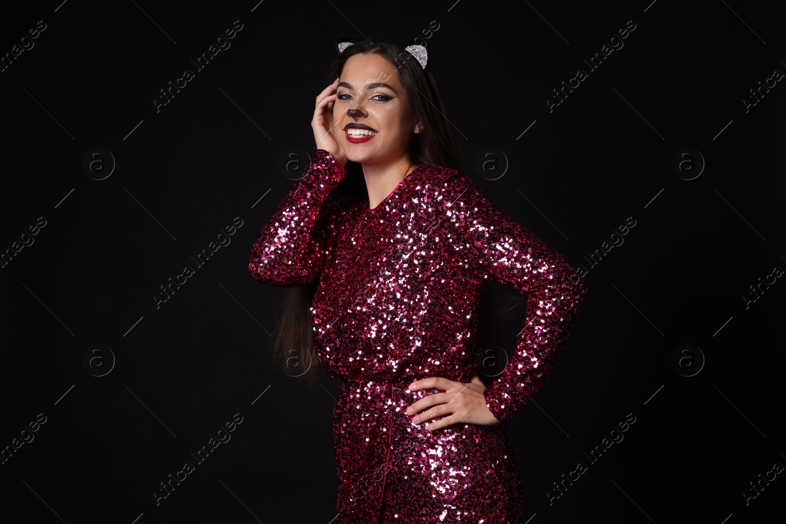 Photo of Charming woman with cat makeup and ears on black background