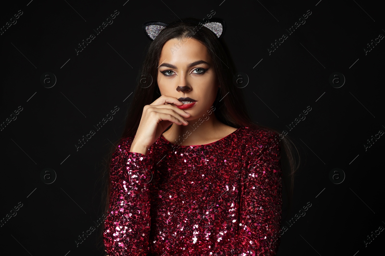 Photo of Charming woman with cat makeup and ears on black background