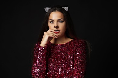 Photo of Charming woman with cat makeup and ears on black background