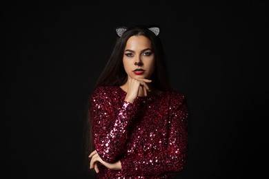 Charming woman with cat makeup and ears on black background